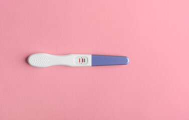Positive pregnancy test on a pink background.