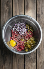 beef tartare on a dark plate in the hands of a man