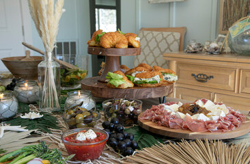 Beautiful charcuterie table set up for lunch with meats, cheeses, sandwiches, and vegetables.