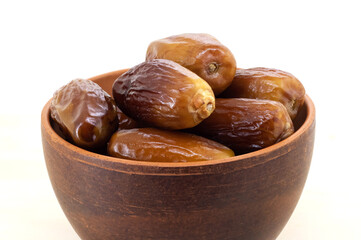 Ripe dates in a brown cup on a white isolated background