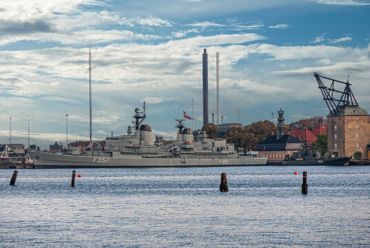 Copenhagen, Denmark - September 13, 2010: HDMS Peder Skram museum war frigate docked at Holmen in harbor under blue cloudscape. Historic crane nearby and tall chimneys