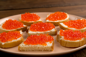 Naklejka na ściany i meble Canape with red caviar in butter on a beige plate.