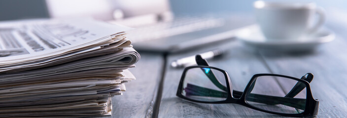 Newspapers with glasses and laptop.
