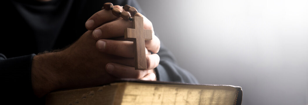 prayer man holding Bilbe with cross