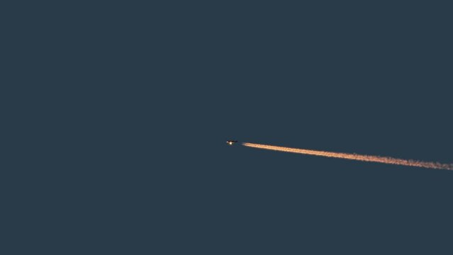 Trails from passenger commercial airplane flying at sunset,sunrise, chemtrails conspiracy theory concept