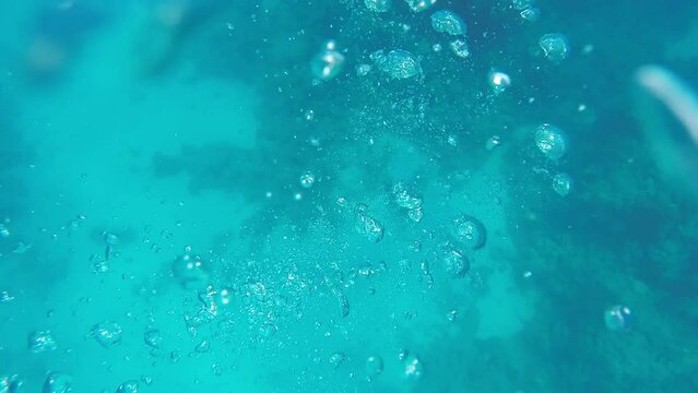 Many large bubbles in the azure sea water after scuba diving