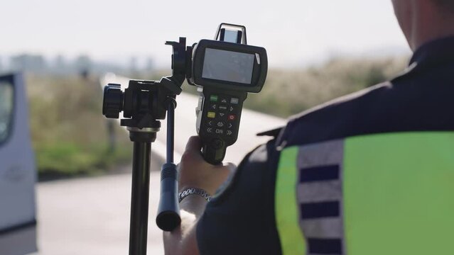 Road police officer using a mobile radar on the highway controlling traffic vehicle car speed, monitoring highway traffic violations. Police traffic speed control camera, slow motion