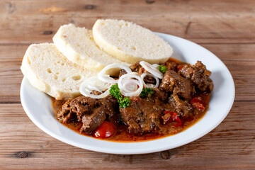 Beef goulash and dumplings (knedliky) on table from Czech Republic