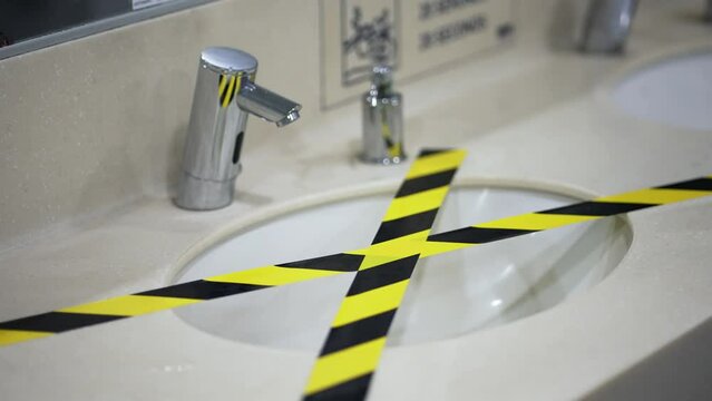 Public toilet sink is covered with a restricted film tape, the bathroom is forbidden to use