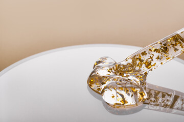 Pipette and gel cosmetic products with gold in a Petri dish on beige background