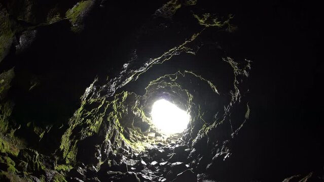 Arnarker cave lava tube Iceland, looking out entrance to bright light, sliding shot