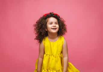 portrait of a girl in a yellow dress cute attractive cute cheerful cheerful little girl .isolated pink background.