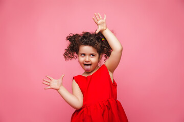 emotional portrait of a little girl in a red dress on a pink background.