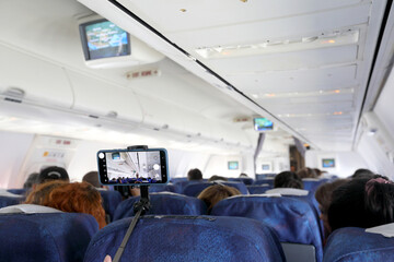 A passenger films the interior of the plane with his mobile phone.