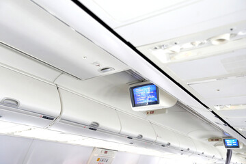 Information monitors for passenger in white interior of modern aircraft.