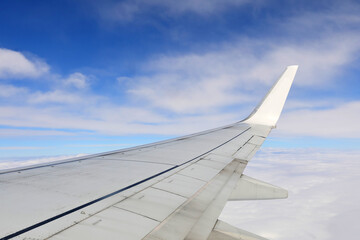 View from airplane window on the wing against white clouds and blue sky.Flying and traveling above the clouds.