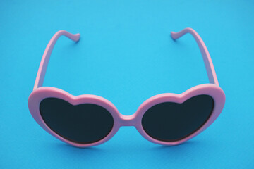 Dark glasses in a pink frame on a blue background.