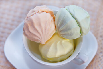 Delicious fresh multicolored air marshmallow lies on a serviced table in saucer