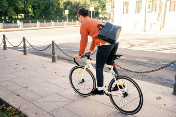 The person is a freelancer with a briefcase, a cyclist going to work, eco transport in the city, rear view.