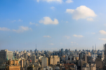 Fototapeta na wymiar Cidade de São Paulo vista do alto, com edifícios, torres antenas e céu azul com nuvens.