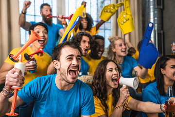 Multiracial joyful sport fans watching game on TV at home - Supporters having fun on sofa for...