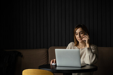 Beautiful caucasian woman concentrated while using laptop in a modern workspace. Cute young business woman speaking on the phone