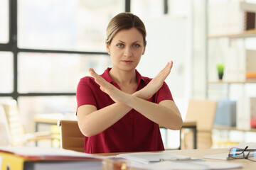 Woman manager shows Stop gesture at desk in company office