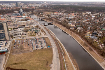 Drone photography of river going through city and bridges through it during cloudy spring day.