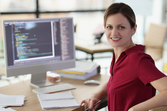 Smiling woman app developer writes code in company office