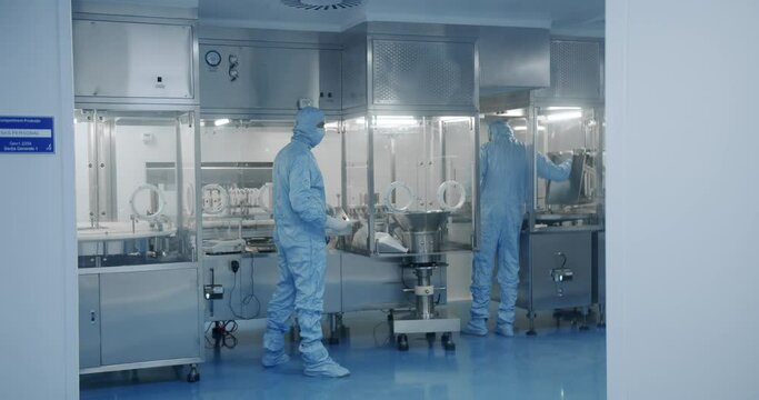 Sterile Pharmaceutical Manufacturing Laboratory where Scientists in Protective Coveralls. Factory Cleanroom. Pharmaceutical, Biotechnological and Semiconductor Creating Manufacturing Process.