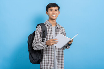Young asian college student wearing flannel shirt carrying backpack holding and reading book...