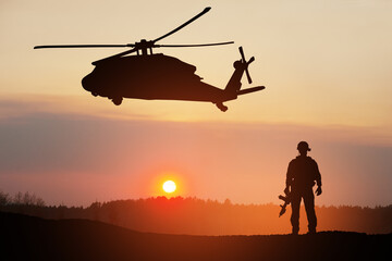 Naklejka na ściany i meble Silhouettes of helicopter and soldier on background of sunset. Greeting card for Veterans Day, Memorial Day, Air Force Day. USA celebration.