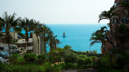 Panoramic view of the Funchal coastline with hotel buildings and a lone sailboat in the ocean