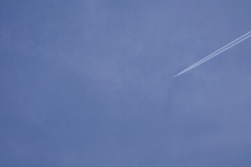 Samolot leci wysoko na niebie i pozostawia za sobą smugę - obrazy, fototapety, plakaty