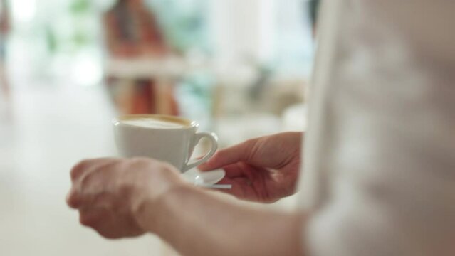 Service, cafe and waiter with a coffee for a customer, serving a drink and giving an order. Cafeteria, walking and barista with a cappuccino for a peron in a cafe, restaurant or store in the morning