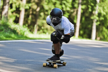 Hipster rides by mountain road on longboard or skateboard