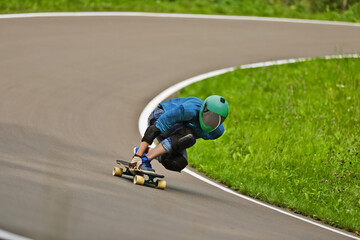 Obraz premium A guy wearing a helmet is riding his longboard on a country road
