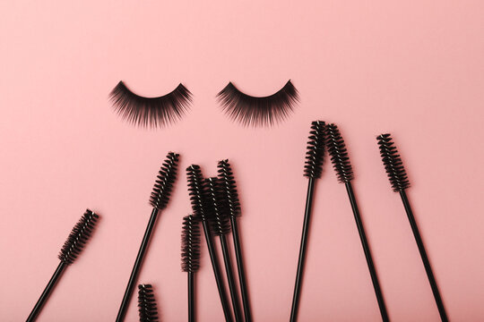 Eyelash extension brushes on a pink background. Brush for combing extended and false eyelashes. Brush for straightening eyelashes and eyebrows.