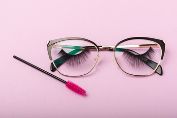 Composition with false eyelashes and glasses, mascara and eyelash brushes, eyelash curlers on a...