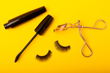 Composition with false eyelashes, mascara and eyelash brushes, eyelash curlers on a yellow background. Makeup artist tools. Beauty concept. Compose. Place for text. Place to copy. Flatley. MOCAP.