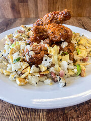 Kentucky hot wings sweet and sour with egg fry rice, black sesane seads served on a light blue plate, wooden background Clouse Up.