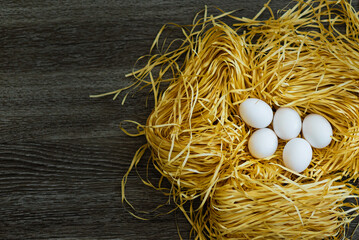 Chicken white eggs lie in a decorative nest on a wooden background. Happy easter.Greetings and presents for Easter Day celebrate time. Flat lay ,top view.