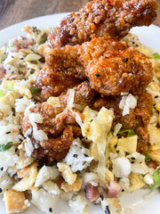 Kentucky hot wings sweet and sour with egg fry rice, black sesane seads served on a light blue plate, wooden background Clouse Up.