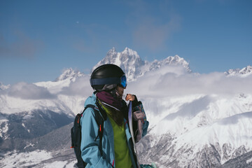 Fototapeta na wymiar Snowboarder woman standing with snowboard beautiful mountain peaks covered with snow on background