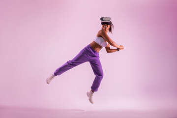 Sporty black woman playing tennis in virtual reality googles, lady swinging a virtual tennis bat,...