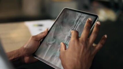 Close up hands of african doctor veterinarian thinking about diagnosis while looking at results dog pet patient online x-ray scan procedure using tablet gadget at hospital office