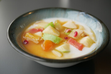 fresh fruits mixed with yogurt in a bowl on table 