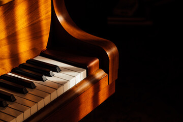 closeup of black and white pianos keys on wooden baby grand piano in the sun