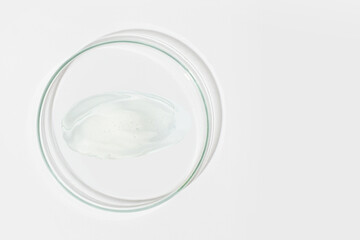 Petri dish on a light background. With a smear of clear gel. Cosmetic gel, lubricant, gel. View from above