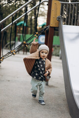 a portrait of a small child playing on the playground of an ordinary European town in cloudy weather
